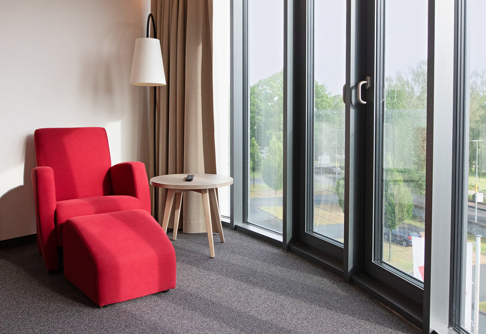 Hotelzimmer im Hotel Susato - Roter Sessel an Fensterfront
